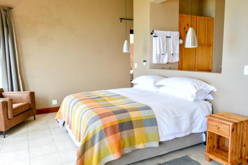 a bedroom with a bed with a colorful blanket and a chair at 4 Zwaan in Jeffreys Bay
