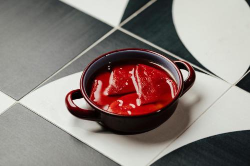 a black cup filled with red sauce on a tile floor at Radisson Collection Hotel, Magdalena Plaza Sevilla in Seville