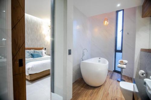 Becquer Hotel Guadalajara في غواذالاخارا: حمام مع حوض وغرفة نوم مع سرير