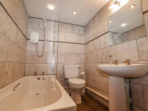 Un baño con bañera, lavabo e inodoro. en 2 The Old Coach House, en Ambleside