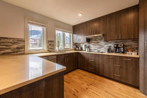 cocina con armarios de madera y encimera en Private Hot Tub / Yard /Patio - A/C- Mountain View Vacation Home en Canmore
