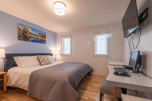 a bedroom with a bed and a desk with a computer at Private Hot Tub - Private Front Yard with Mountain View Patio in Canmore