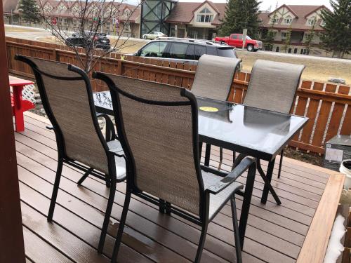 three chairs and a table on a deck at Private Hot Tub - Private Front Yard with Mountain View Patio in Canmore