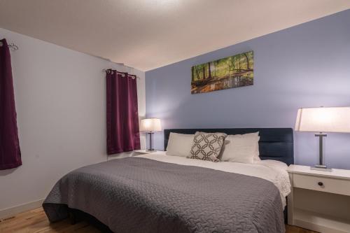 a bedroom with a bed and two tables and two lamps at Private Hot Tub - Private Front Yard with Mountain View Patio in Canmore
