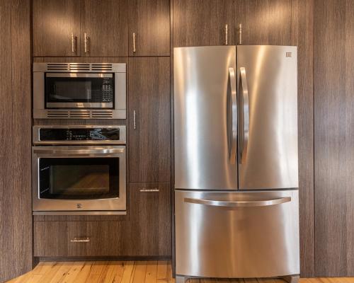 a stainless steel refrigerator and microwave in a kitchen at Private Hot Tub - Private Front Yard with Mountain View Patio in Canmore