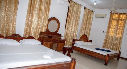 a bedroom with two beds and a mirror and curtains at SULKHAN SERVICED APARTMENT in Chukwani