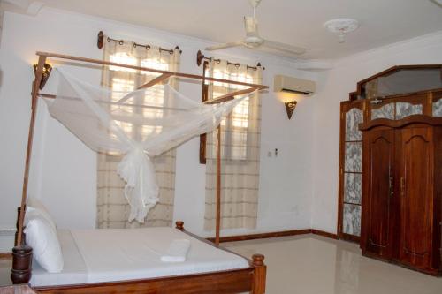 a bedroom with a bed with a mosquito net at SULKHAN SERVICED APARTMENT in Chukwani