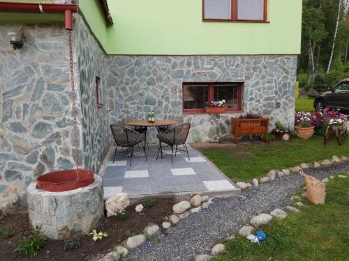 a patio with a table and chairs next to a stone building at Vila Kamila in Tatranska Strba