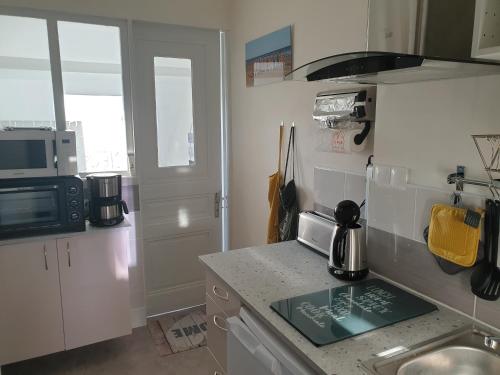 une petite cuisine avec un évier et un micro-ondes dans l'établissement le Home Sweet Home d'Alice!!! à la Villa Alice Roger, à Dunkerque