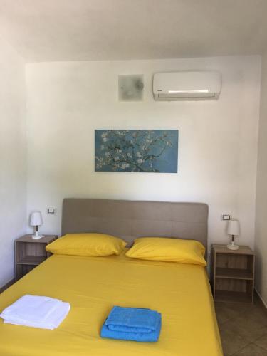 una camera con letto giallo e 2 comodini di Casa Teresa a Porto Pino a Porto Pino