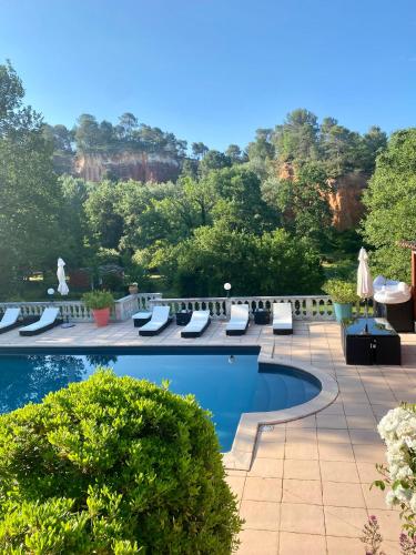 - une piscine avec des chaises longues et une vue sur les arbres dans l'établissement Villa des Roses, à Roussillon
