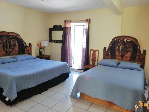 a bedroom with two beds and a window at Hotel Chely in Bernal