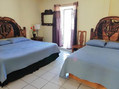 a bedroom with two beds and a window at Hotel Chely in Bernal