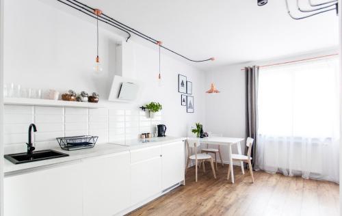 a white kitchen with a table and chairs at Check in Szczecin in Szczecin