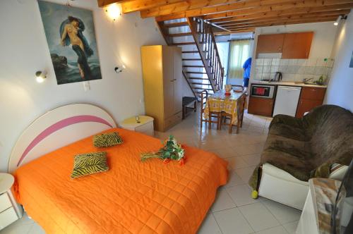 a bedroom with an orange bed and a kitchen at Alessandro in Sidari