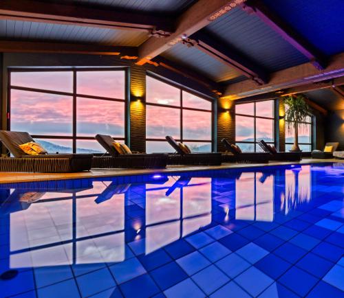 a swimming pool with chairs in a building at Natura Hotel Bodenmais - inkl Soft- und Heißgetränkeflat in Bodenmais