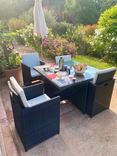 een tafel en stoelen met een tafel en een parasol bij Villa des Roses in Roussillon