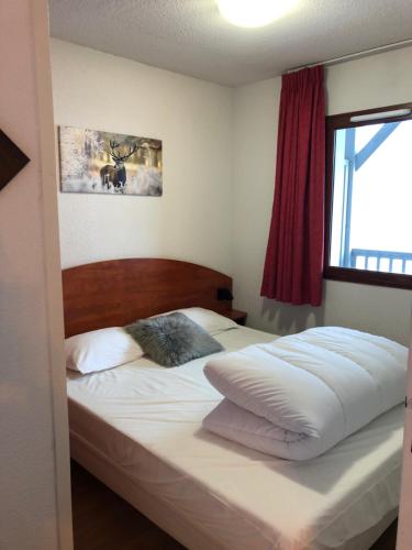 una camera da letto con un letto con lenzuola bianche e una finestra di Appartement 2 chambres en duplex à La Mongie a La Mongie