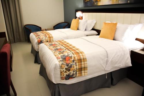 2 camas en una habitación de hotel con sábanas blancas y almohadas de color naranja en Park Town en Yeda