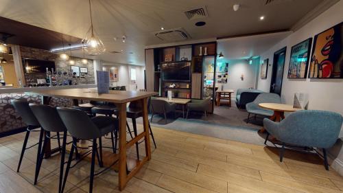 a restaurant with a bar and some chairs and tables at Holiday Inn Brentwood by IHG in Brentwood