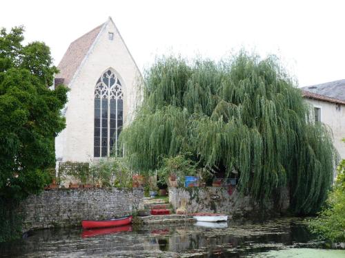 a church with a weeping willow tree and boats in the water at Demeure VERTEUILLAISE in Verteuil-sur-Charente