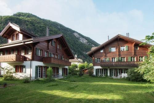 a large building with a grass yard in front of a mountain at CityChalet in Interlaken
