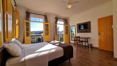 a bedroom with a bed and a table and windows at Pousada Imperial Cidade in Ouro Preto