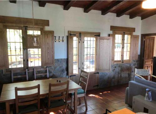 a living room with a table and chairs and windows at Vuelos de Montaña l in Montánchez