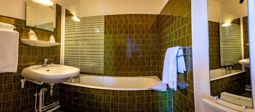 a bathroom with a tub, sink and mirror at Hotel Le Boischaut - Citotel Chateauroux in Châteauroux