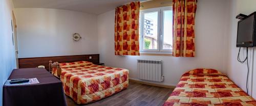 a bedroom with two beds and a tv and a window at Hotel Le Boischaut - Citotel Chateauroux in Châteauroux