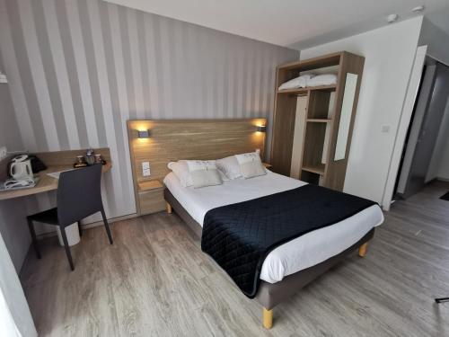 a hotel room with a bed and a desk at Hotel Logis Au Moyne de Saire in Réville
