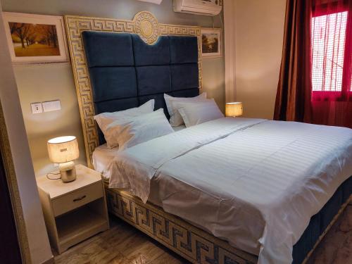 a bedroom with a large bed with a blue headboard at Convivium Home Hotel in Douala