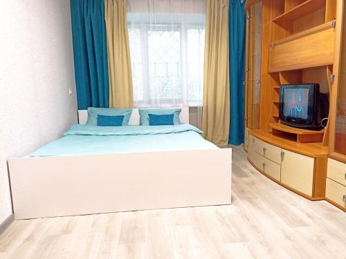 1 dormitorio con 1 cama blanca grande y TV en Светлые апартаменты в 100м от Софиевского парка, en Uman