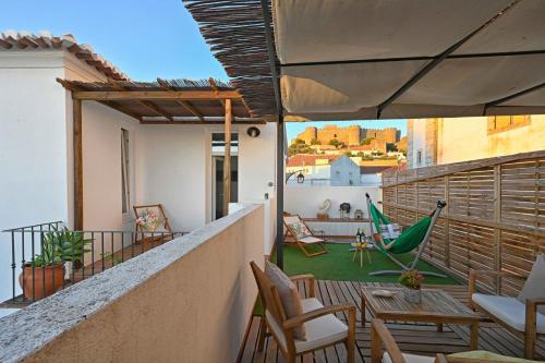a balcony with a patio with chairs and a hammock at Matriz Guest House in Portel
