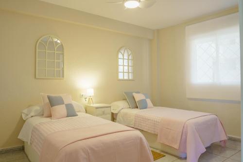 1 dormitorio con 2 camas y 2 ventanas en Club Náutico Altea Playa, en Altea