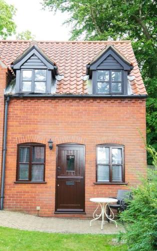 a red brick house with a table in front of it at Pebble Cottage, Cromer in Cromer