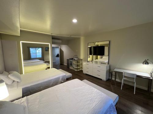 a bedroom with two beds and a desk and a mirror at ASPIRE INN & SUITES Orange in Orange