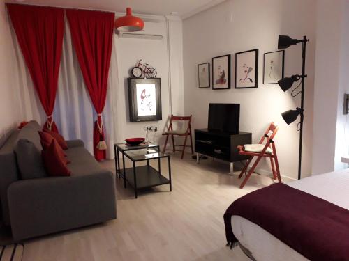1 dormitorio con cama, sofá y TV en El rincón de la Caleta, en Cádiz
