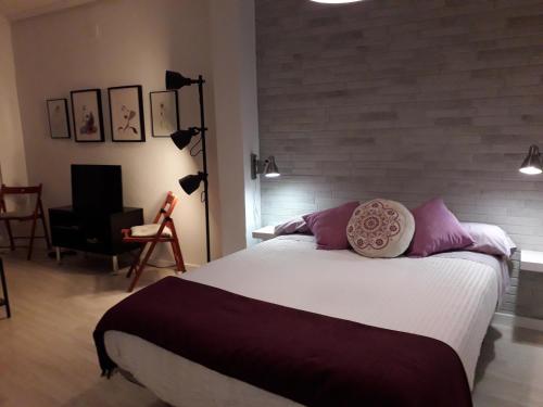 una camera da letto con un grande letto con cuscini viola di El rincón de la Caleta a Cadice