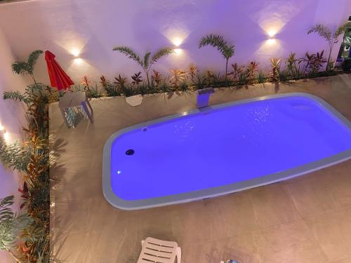 uma grande banheira azul num quarto com plantas em Casa com piscina privativa na Praia do Peró em Cabo Frio