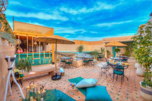 un patio con tavoli, sedie e piscina di riad paradis blanc a Marrakech