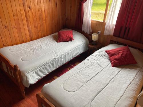 two twin beds in a room with a window at Cabañas Campestres Villarrica in Villarrica