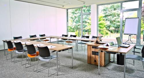 a conference room with tables and chairs and a screen at NP Hotel Ullrich in Elfershausen