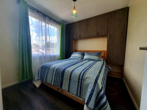 a bedroom with a bed with a blue and white comforter and a window at Álamos de Llancahue in Valdivia