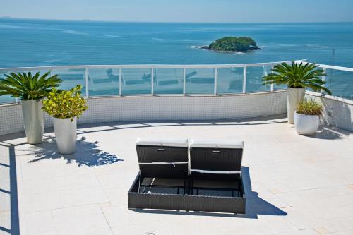 a bench on a patio with the ocean in the background at Mercure Camboriu in Balneário Camboriú