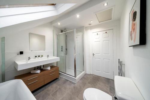 a white bathroom with a sink and a mirror at The Crossroads in Elderslie