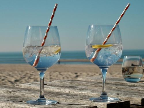 three wine glasses sitting on a table on the beach at Klinket Zoutelande in Zoutelande