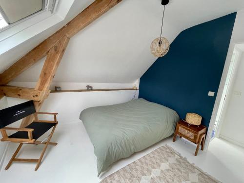 een kleine zolderslaapkamer met een bed en een stoel bij Superbe appartement 4 personnes Le Pouliguen avec vue magnifique sur le port et la mer in Le Pouliguen