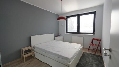a bedroom with a white bed and a red chair at Air-conditioned, 2 room apartment with terrace in Bratislava