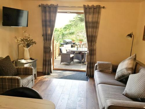 a living room with a couch and a television and a table at Saddleworth Holiday Cottages in Oldham